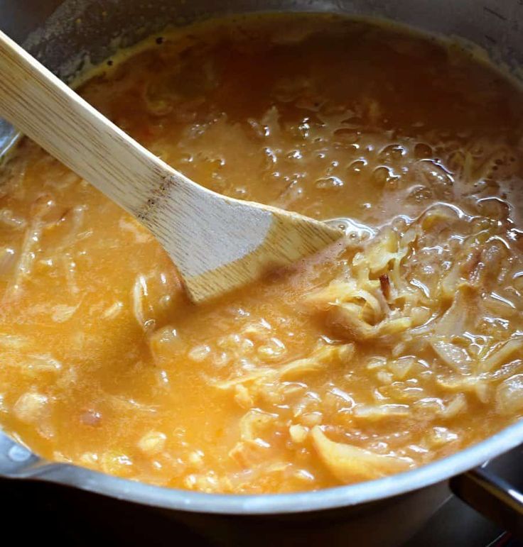 a wooden spoon stirring some food in a pot