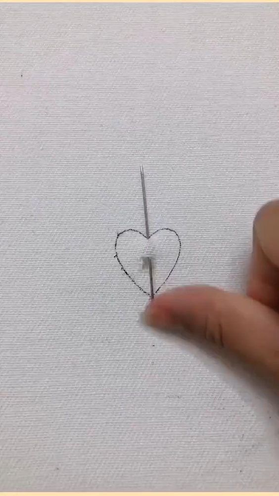 someone is drawing a heart on the paper with a pencil and some pins in it