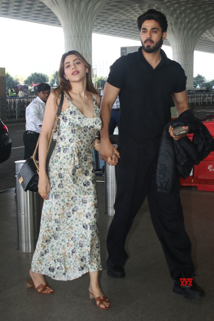 the man and woman are holding hands at the airport