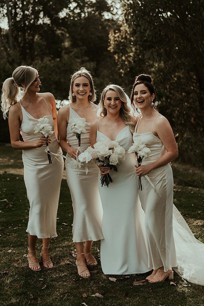 four bridesmaids in white dresses posing for a photo