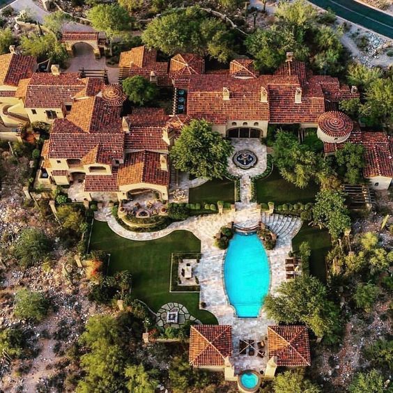 an aerial view of a mansion with a pool in the middle and trees surrounding it