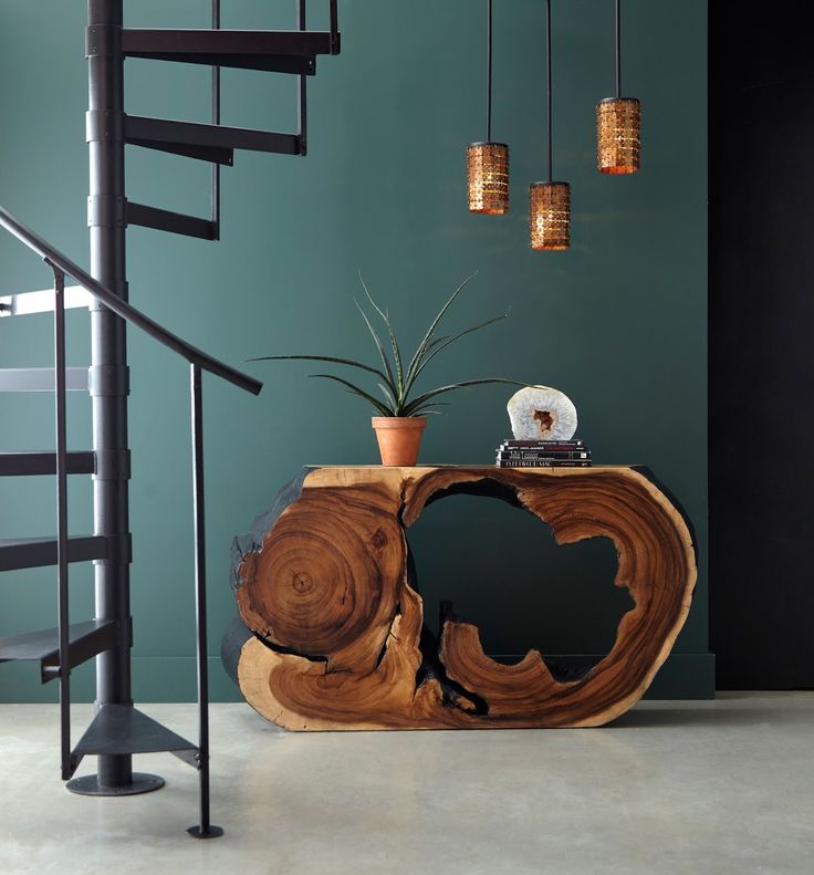 a wooden table sitting next to a spiral stair case in a room with green walls