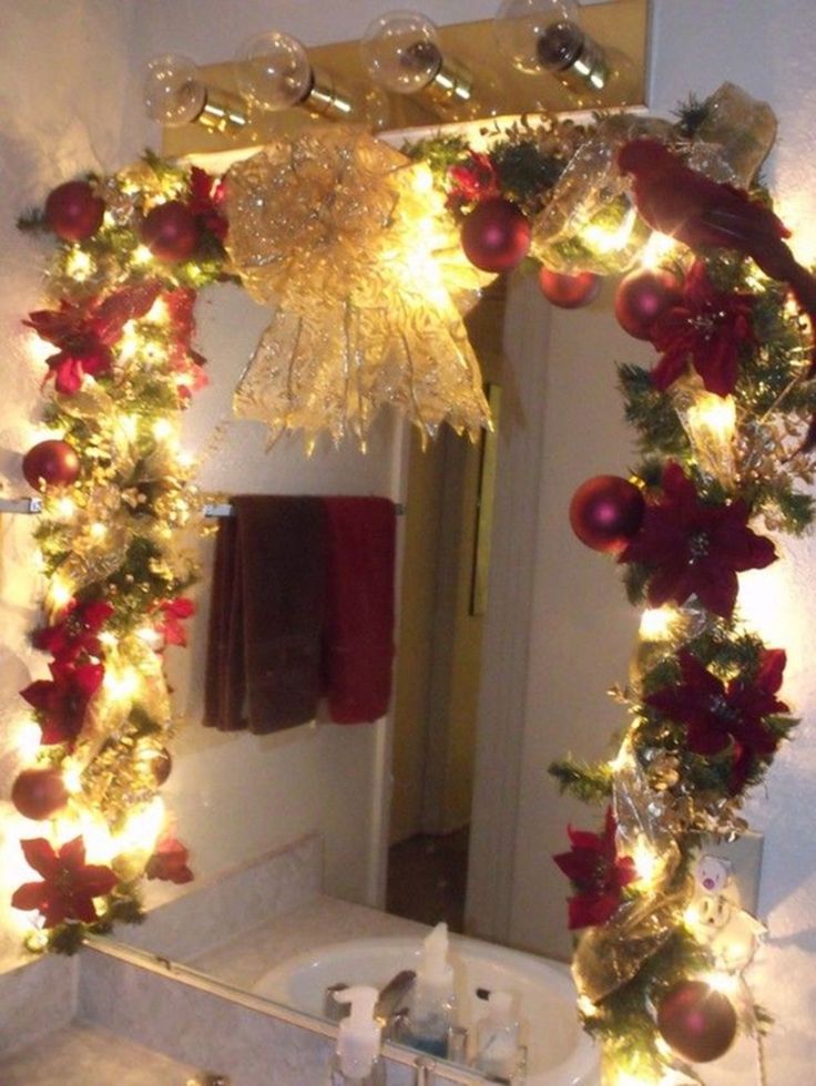 a bathroom decorated for christmas with lights on the mirror and decorations around the sink area