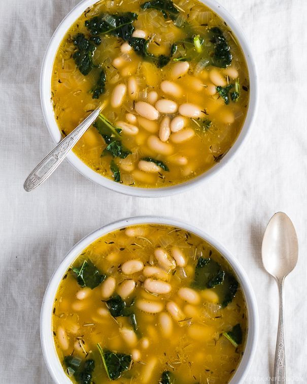 two bowls of soup with beans and spinach