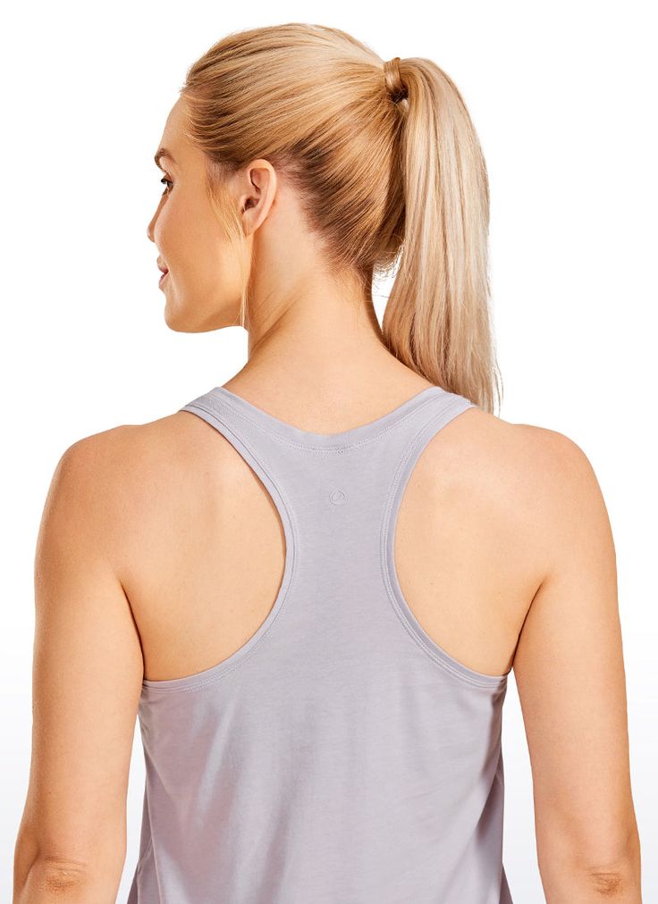 a woman with blonde hair wearing a gray tank top and black leggings, back view