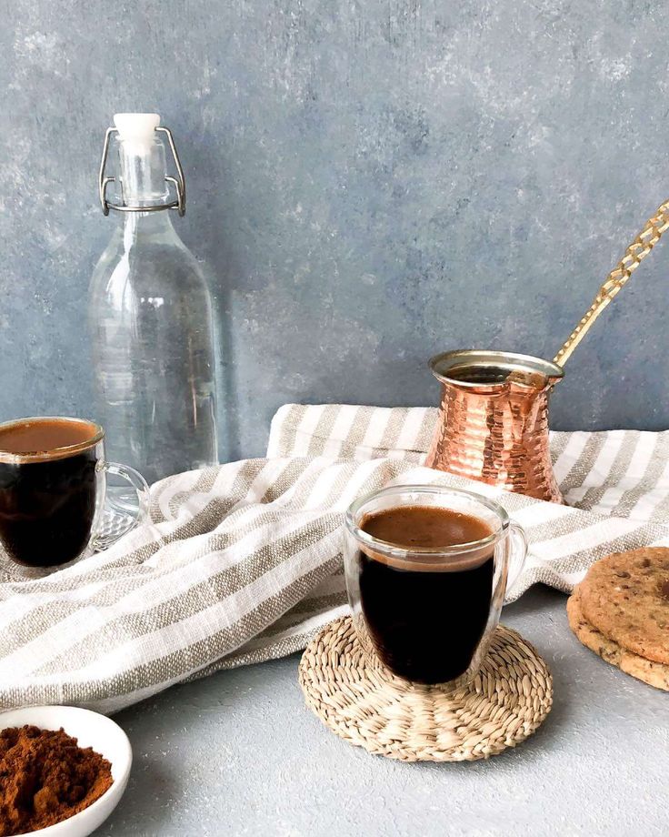 two cups of coffee sit next to some cookies