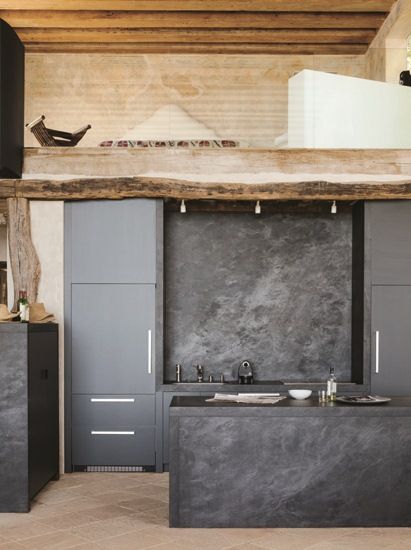 a kitchen with gray cabinets and counter tops in an open concept space that has exposed wood beams on the ceiling