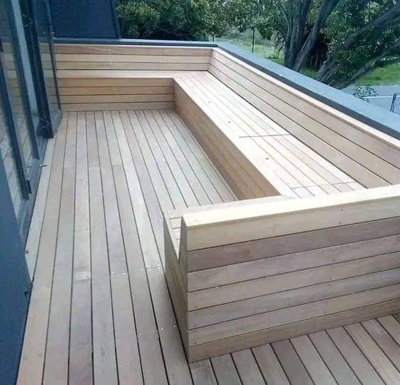 a wooden bench sitting on top of a hard wood floor next to a glass wall