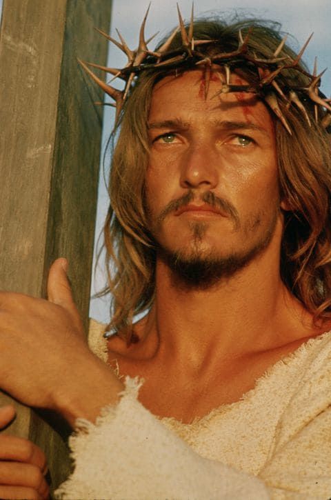 jesus with crown of thorns on his head standing in front of a wooden pole