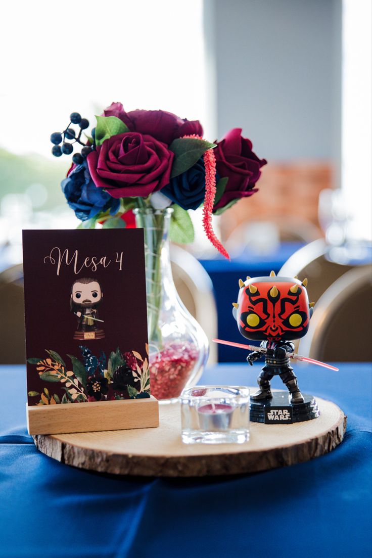 a table topped with a vase filled with flowers and a pop vinyl figure next to a card