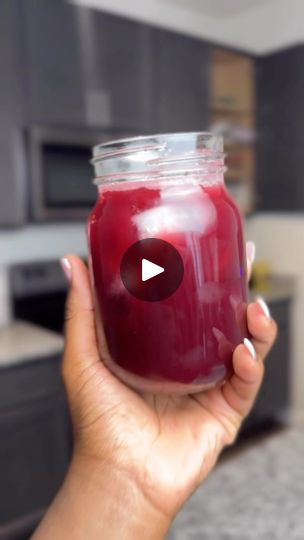 a woman holding a jar of red liquid in her hand