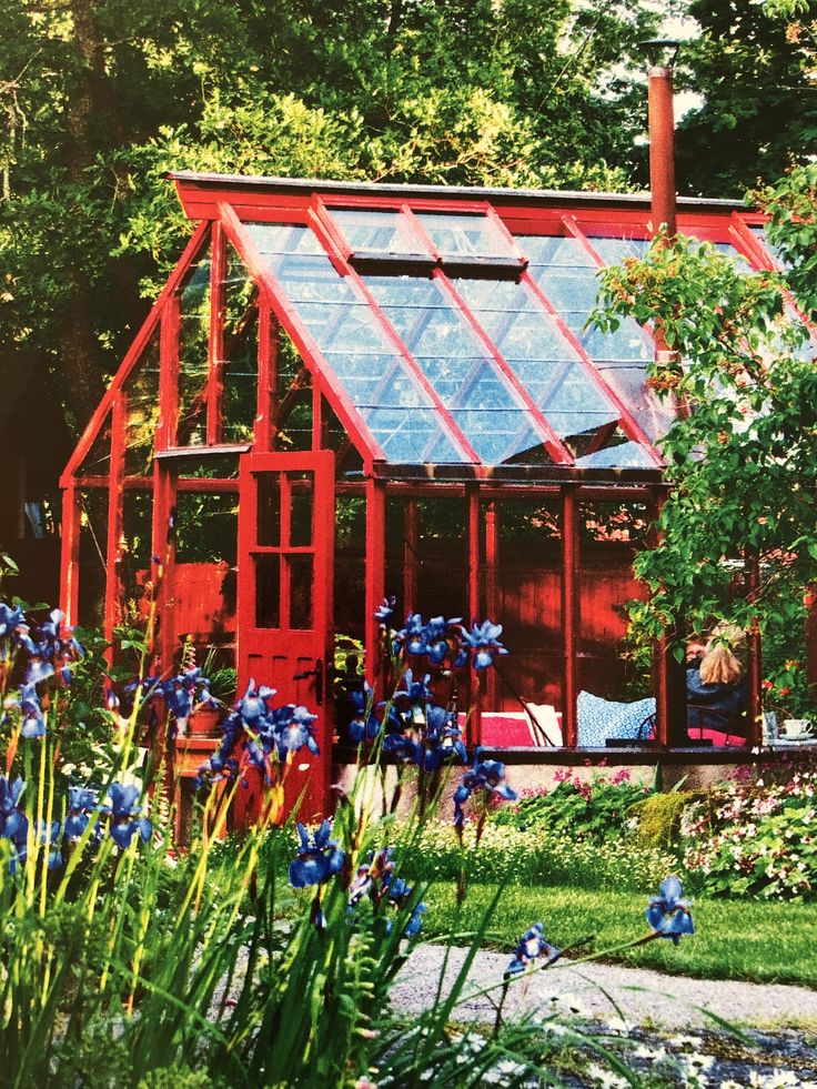 a red house surrounded by blue flowers and greenery