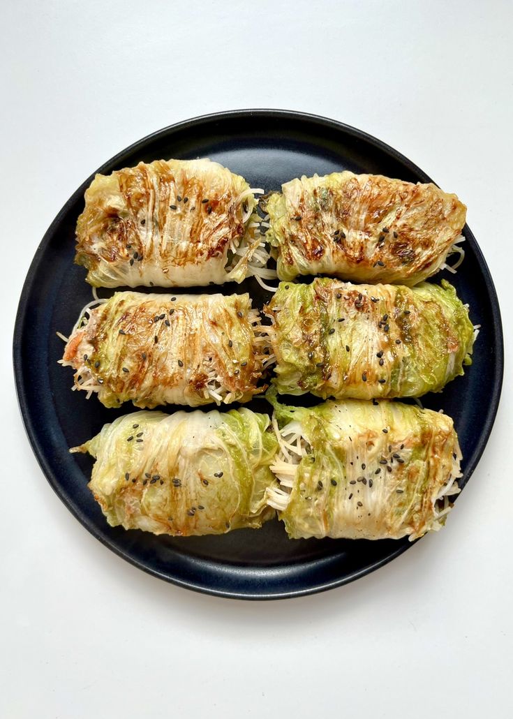 four pieces of stuffed cabbage on a black plate