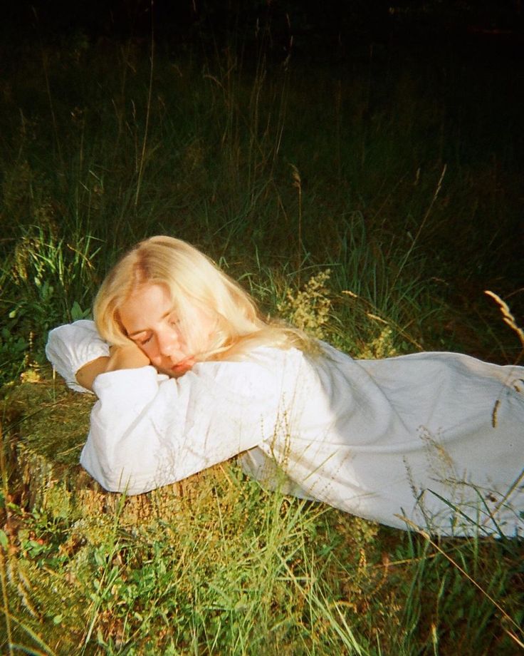 a woman laying in the grass with her eyes closed