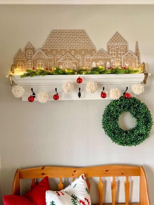 a christmas wreath is hanging on the wall above a crib with pillows and other holiday decorations