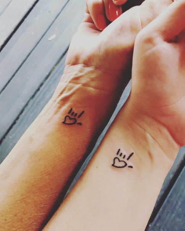 two people holding hands with tattoos on their wrist and one has a dog's paw