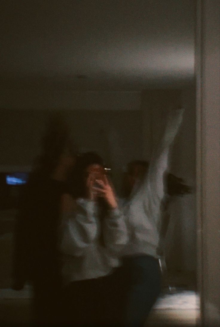 two people are dancing in the dark with their hands up and one person is holding a cell phone