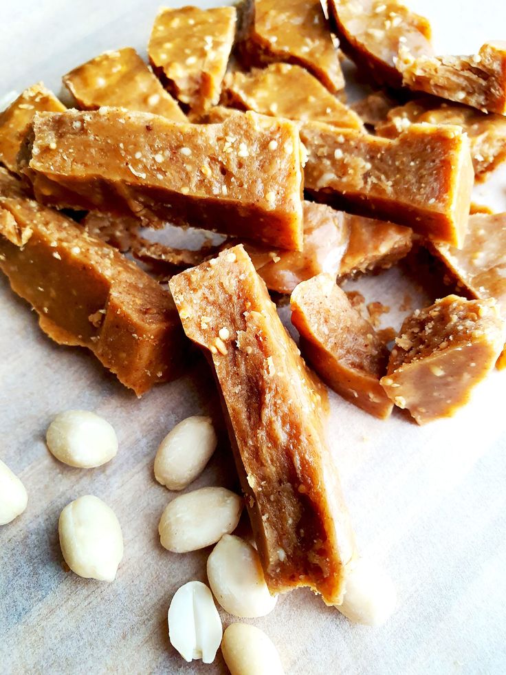 peanuts and peanut brittles are on a cutting board next to some almonds that have been cut into squares