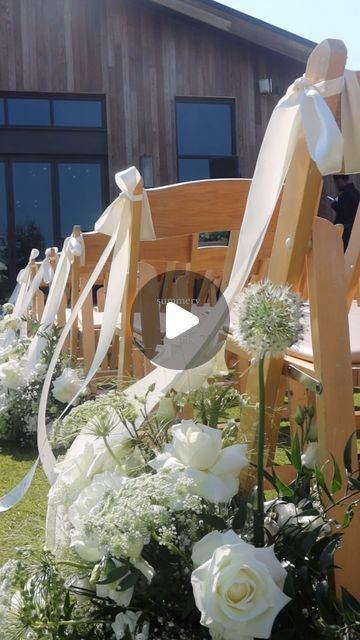 white flowers are lined up along the side of wooden benches with ribbons tied around them