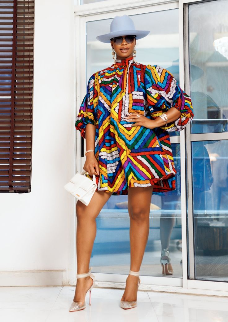 A woman posing in a multicolored African print mini dress. Ankara Short Set For Women, Short Ankara Dresses, African Chic, Clothes Fabric, African Designs, Ankara Fashion, Africa Dress, Ankara Dresses, Classy Design