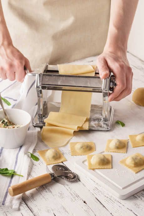 a person is making ravioli on a white table with other ingredients and utensils