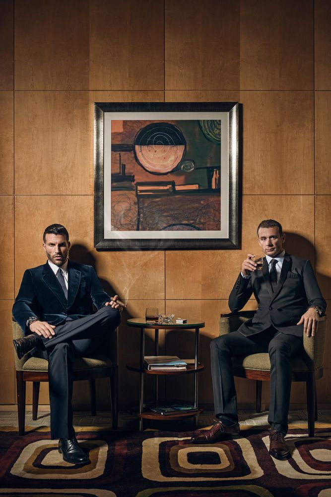 two men in suits are sitting on chairs