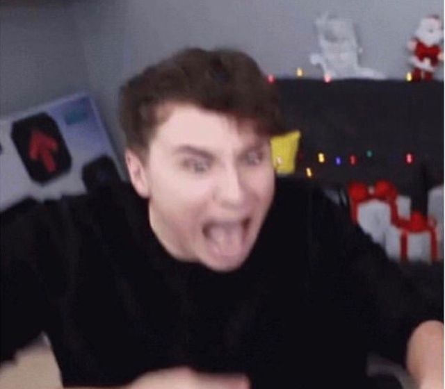 a man making a funny face while sitting in front of a christmas tree with lights on it