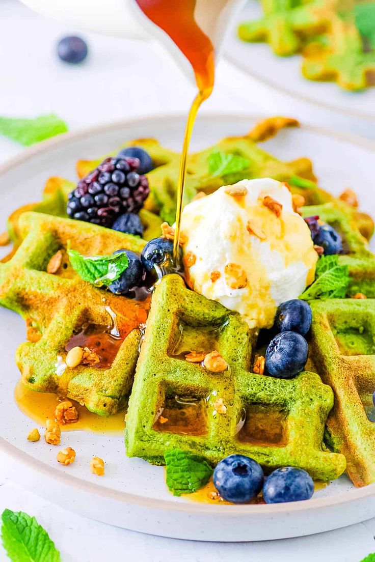 a white plate topped with waffles covered in blueberries and other toppings