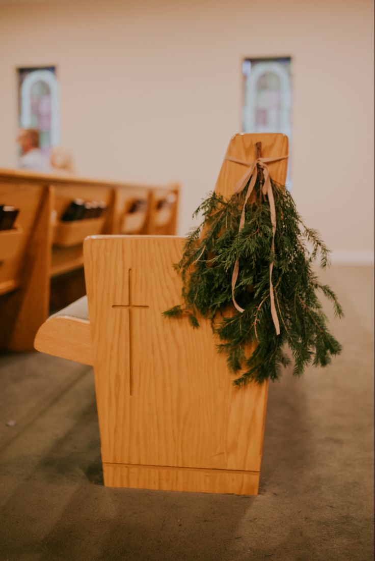 a wooden chair with a wreath on it in front of pews at a church