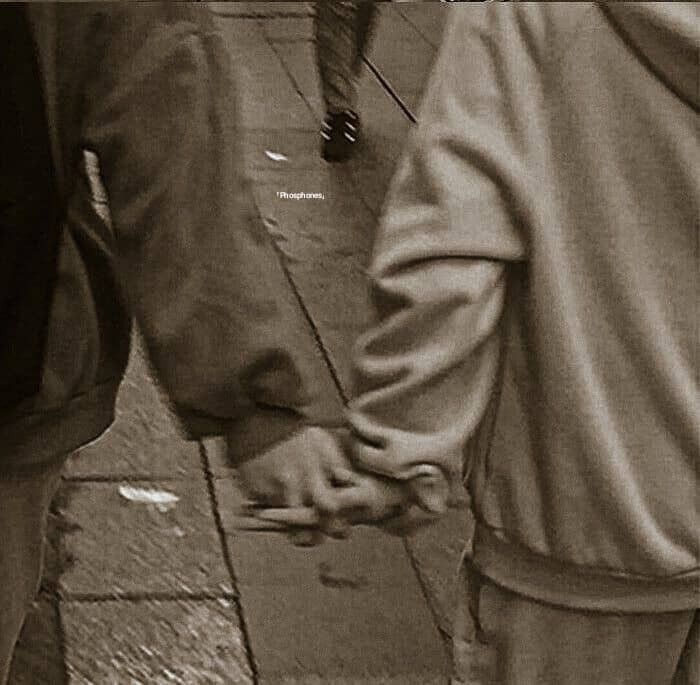 two people holding hands while walking down the street