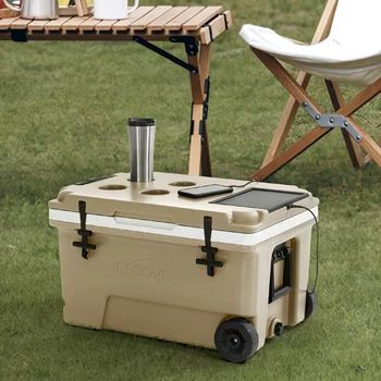 a cooler sitting in the grass next to a table with chairs and cups on it