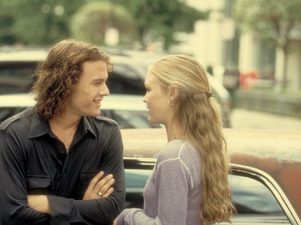 a man standing next to a woman in front of a car