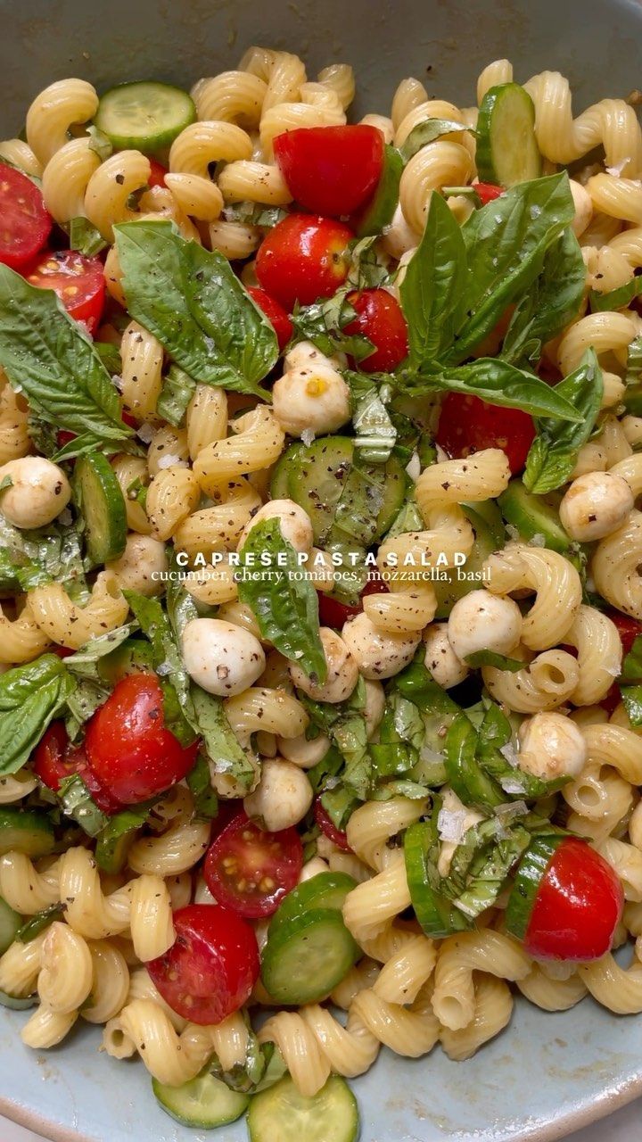 a pasta salad with tomatoes, cucumbers and spinach