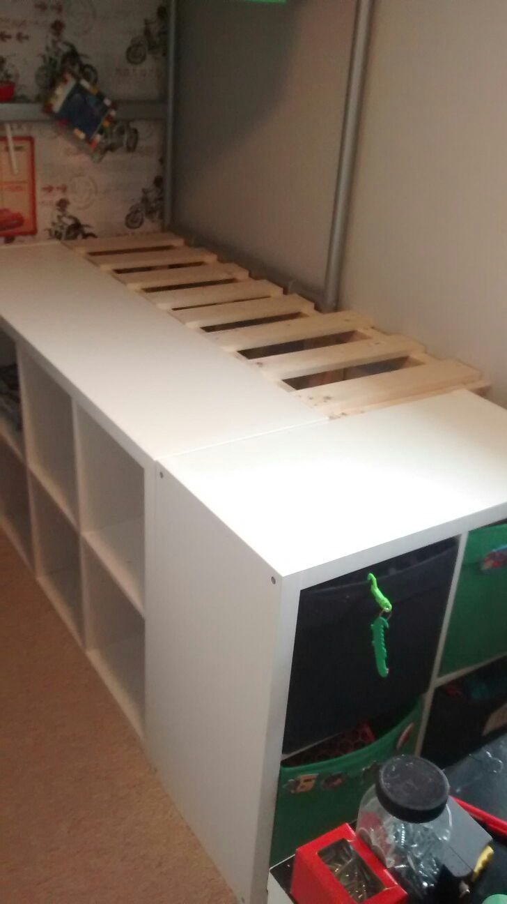 a white bed with drawers underneath it and toys on the bottom shelf in front of it