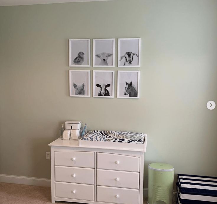 a baby's room with four pictures on the wall and a dresser next to it