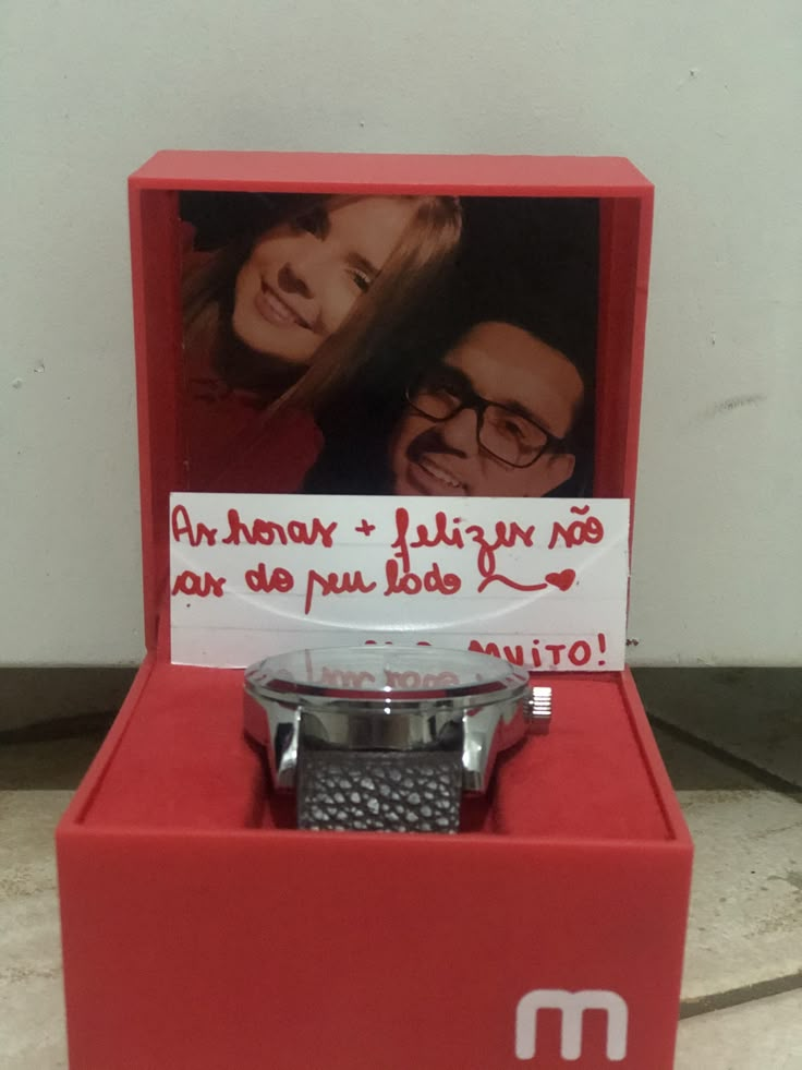 a watch in a red box with a note attached to the front and back of it