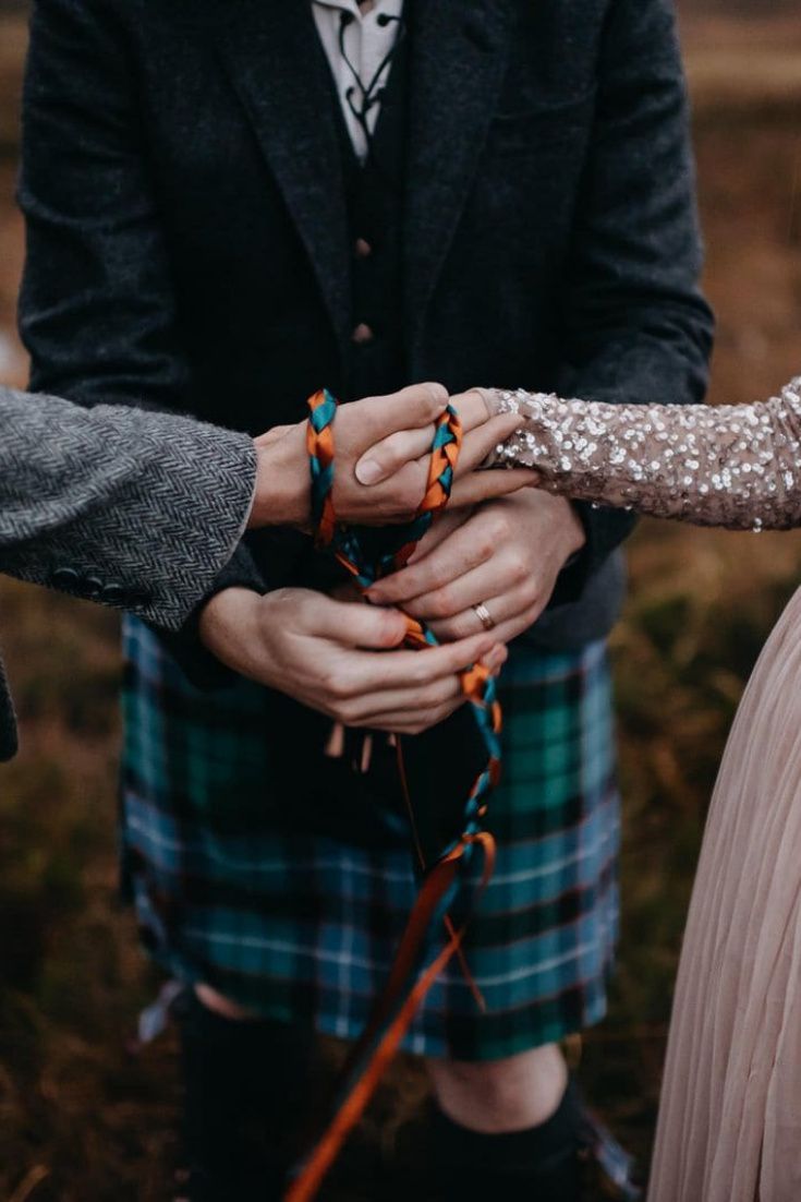 two people in kilts holding hands together