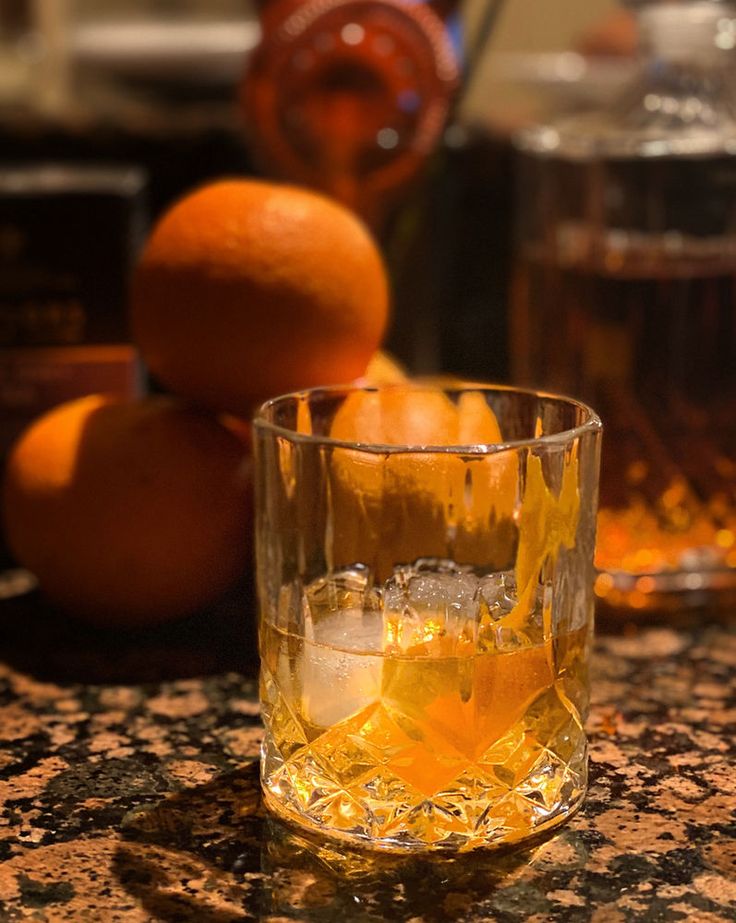 an orange sitting on top of a counter next to glasses