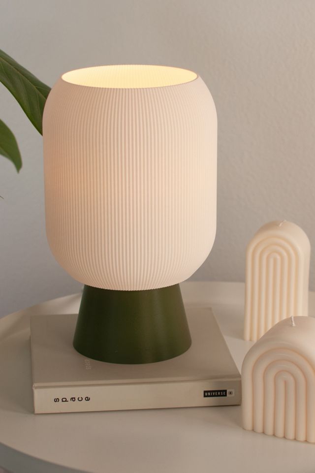 a white lamp sitting on top of a table next to a book and a plant