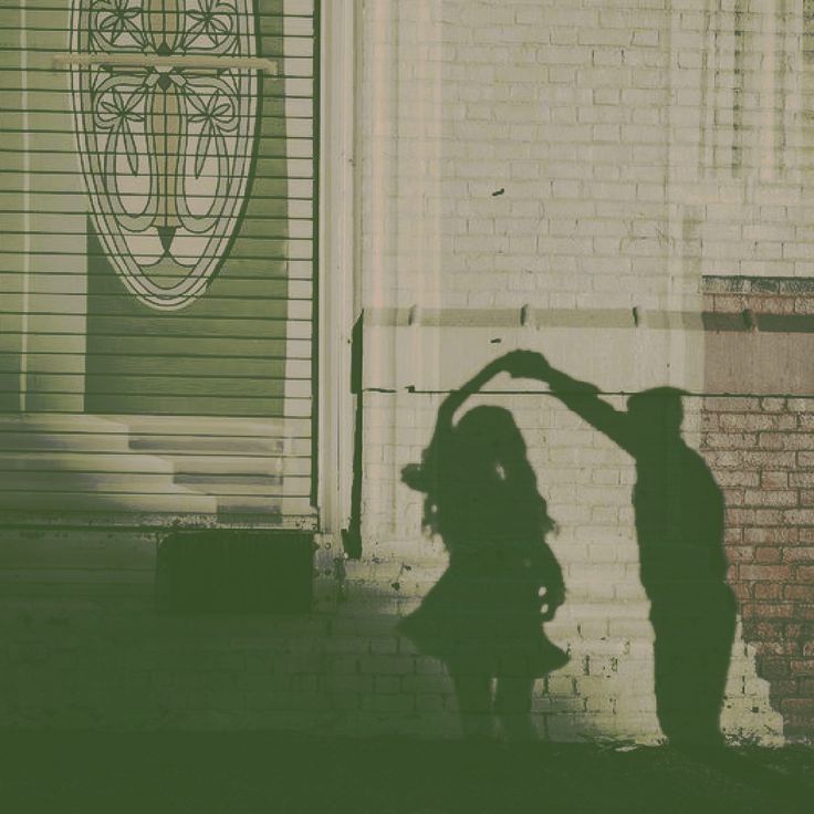 the shadow of two people standing in front of a building