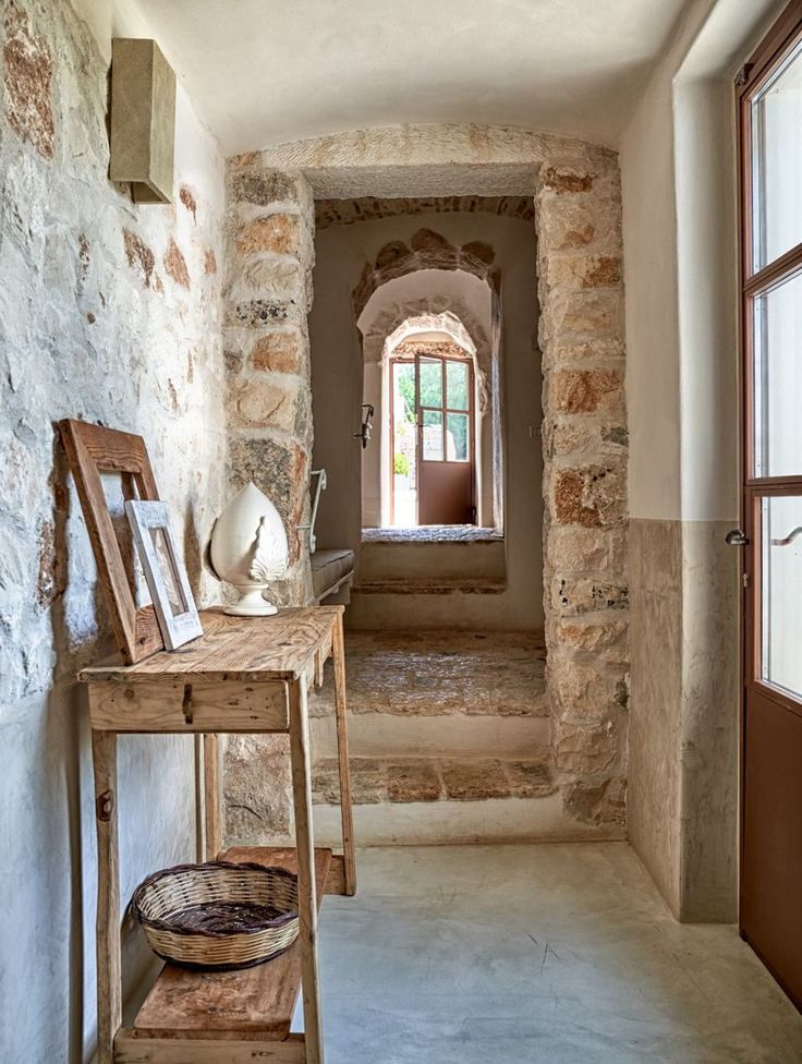 an old stone building with a wooden table and chair in the hallway next to it