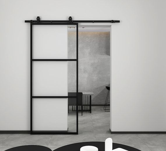 an open door leading to a living room with white walls and black furniture on the floor