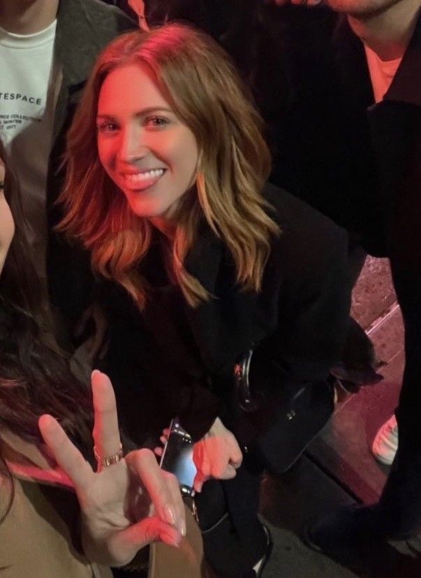 two women making the peace sign with their hands while sitting in front of a group of people