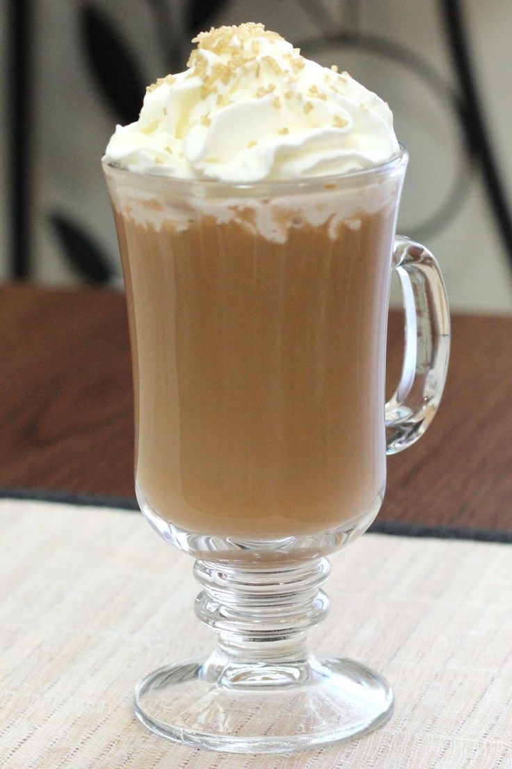 a glass cup filled with whipped cream on top of a wooden table