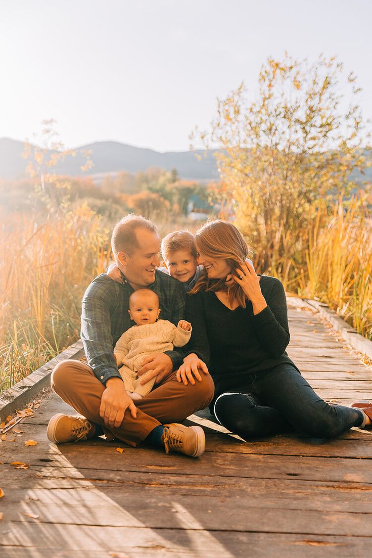 a man, woman and child sitting on a wooden walkway