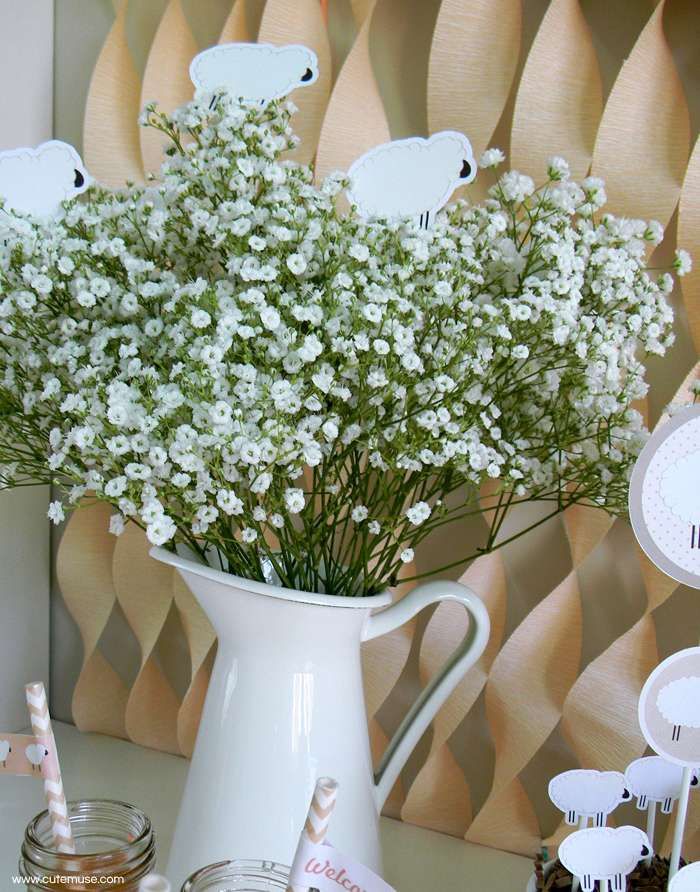 a vase filled with white flowers sitting on top of a table next to plates and cups