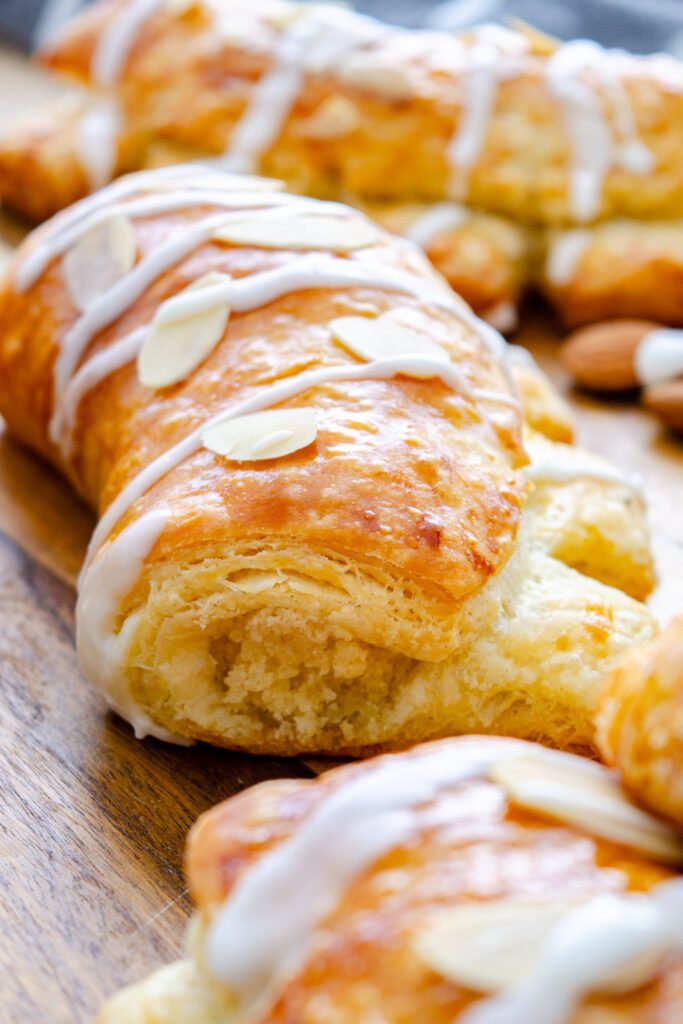 several pastries with white icing and almonds on a wooden table