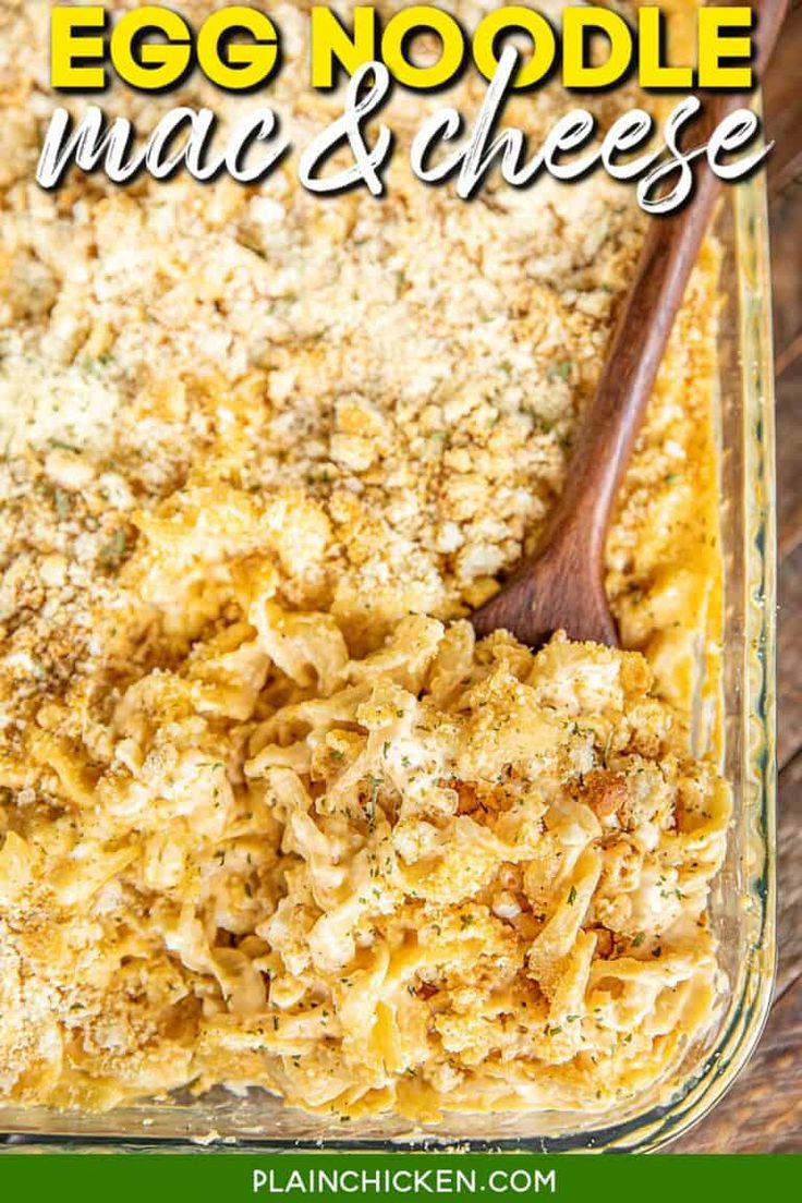 egg noodle mac and cheese in a glass casserole dish with a wooden spoon