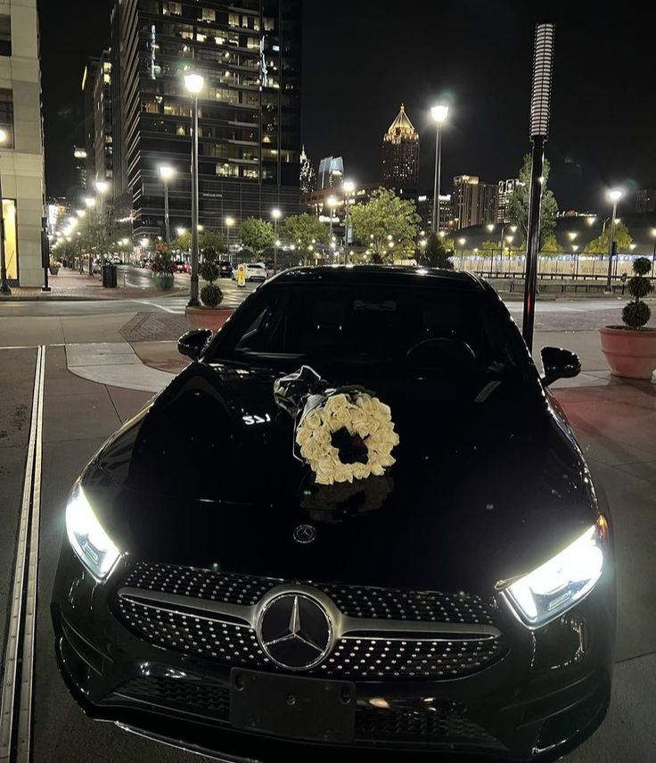 a black car with a wreath on the hood parked in front of a tall building