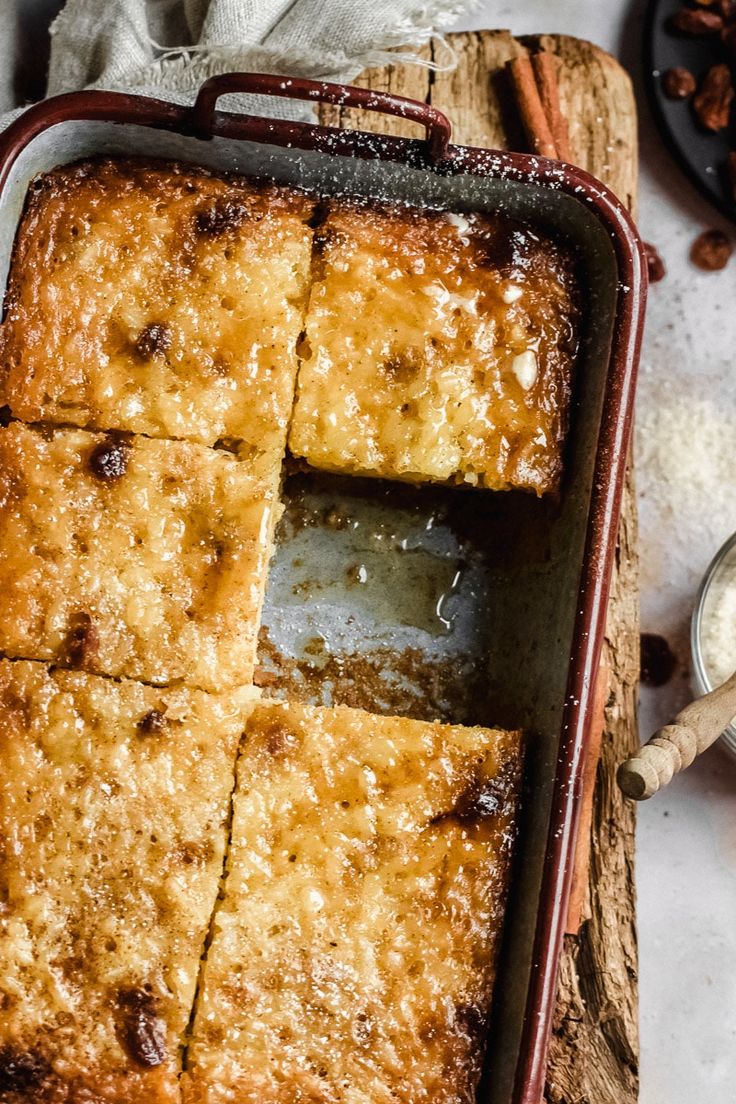 a pan filled with baked goods on top of a wooden cutting board next to a spoon